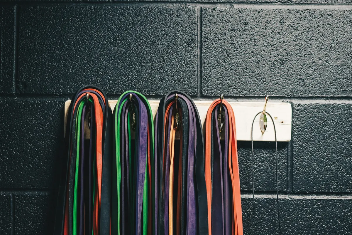 Resistance bands of different thicknesses hanging on a gym wall