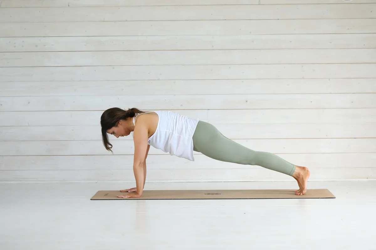 A woman holding a plank with fully straight arms, the position a scapular push-up starts from